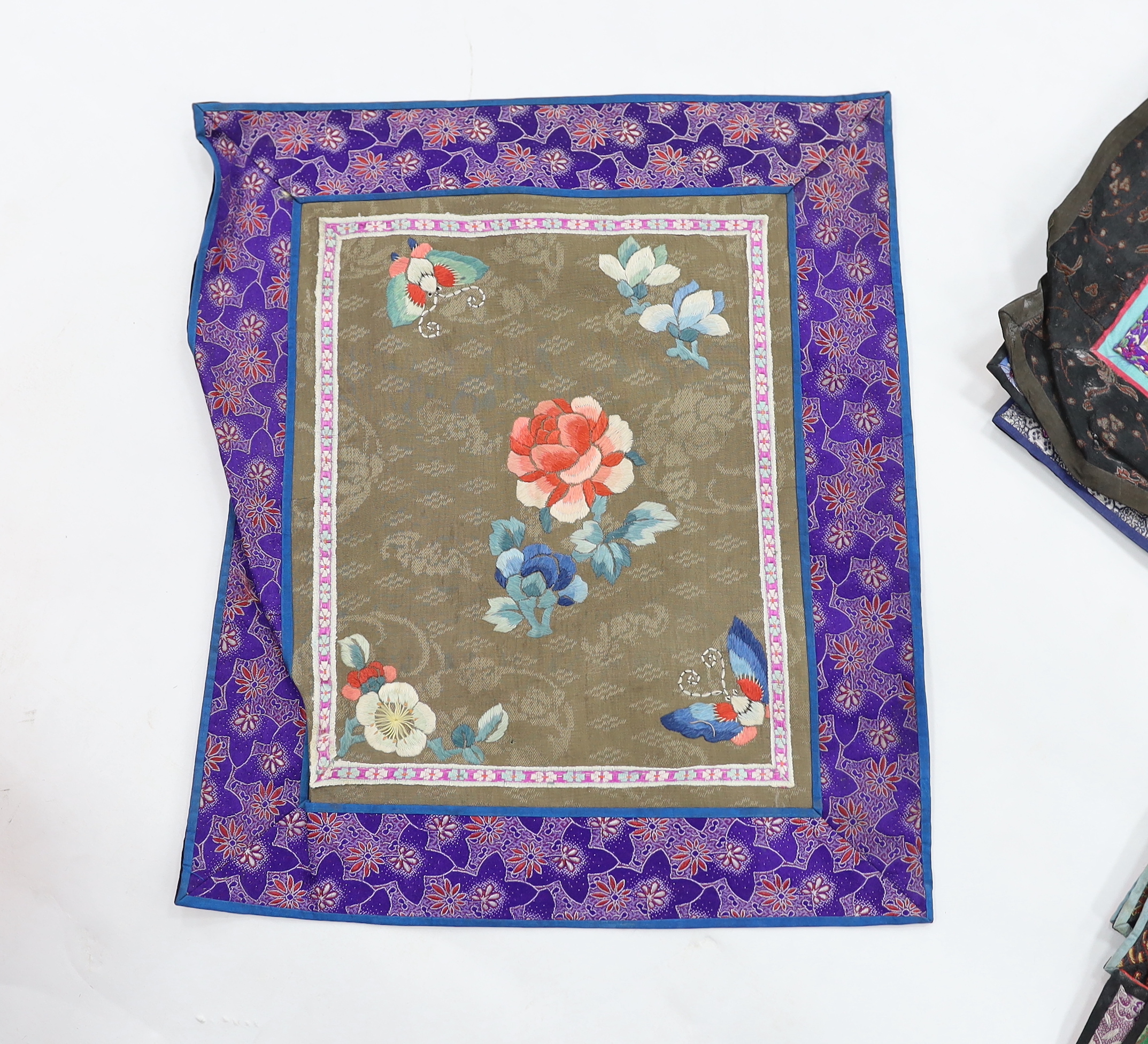 Twenty six assorted Chinese polychrome silk embroidered mats with silk damask borders of varying sizes